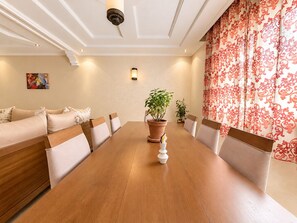 A dining area with a wooden table, chairs, a sofa, and potted plants. - Amazigha - Appartement 3 chambres à 200 m de la plage (essaouira)