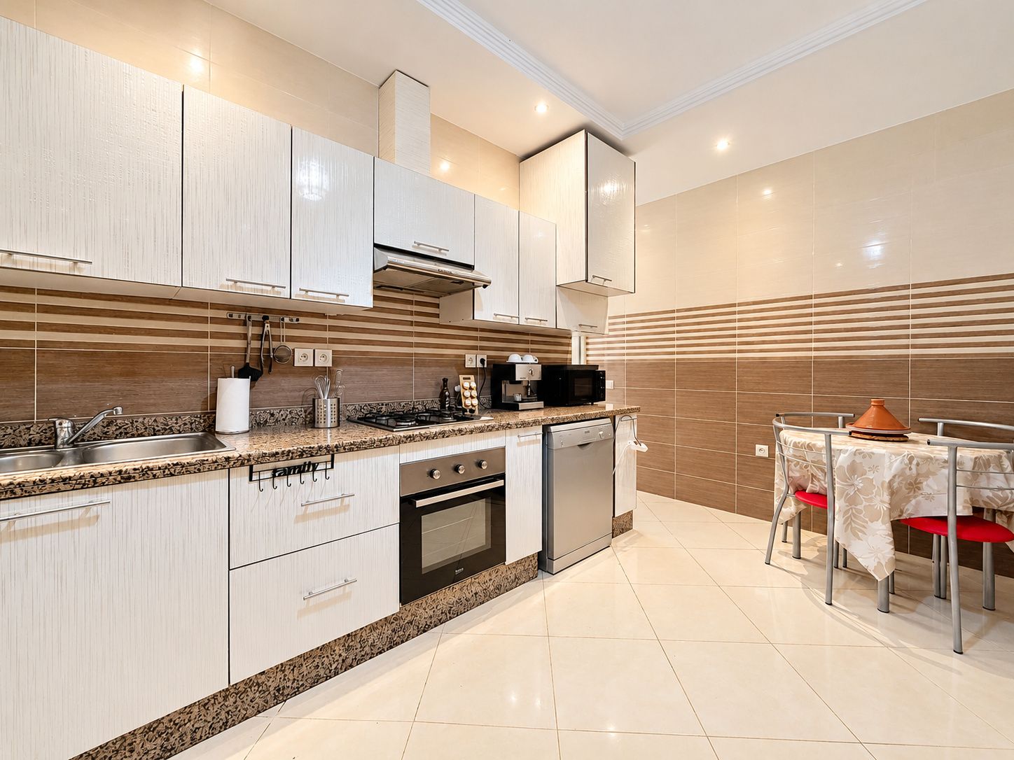 A modern kitchen with a gas stove, oven, microwave, and a dining area with a table and chairs.