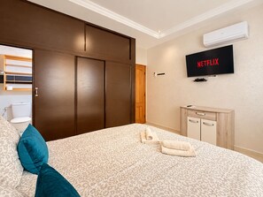 Ein Hotelzimmer mit einem Bett, einem Kleiderschrank, einem Fernseher und einer Klimaanlage.