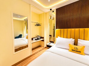 A hotel room with a bed, bedside table, and a mirror. - The Benchmark Hotel (Indore)