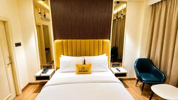 A hotel room with a large bed, a bedside table with a telephone, a chair, and a mirror.