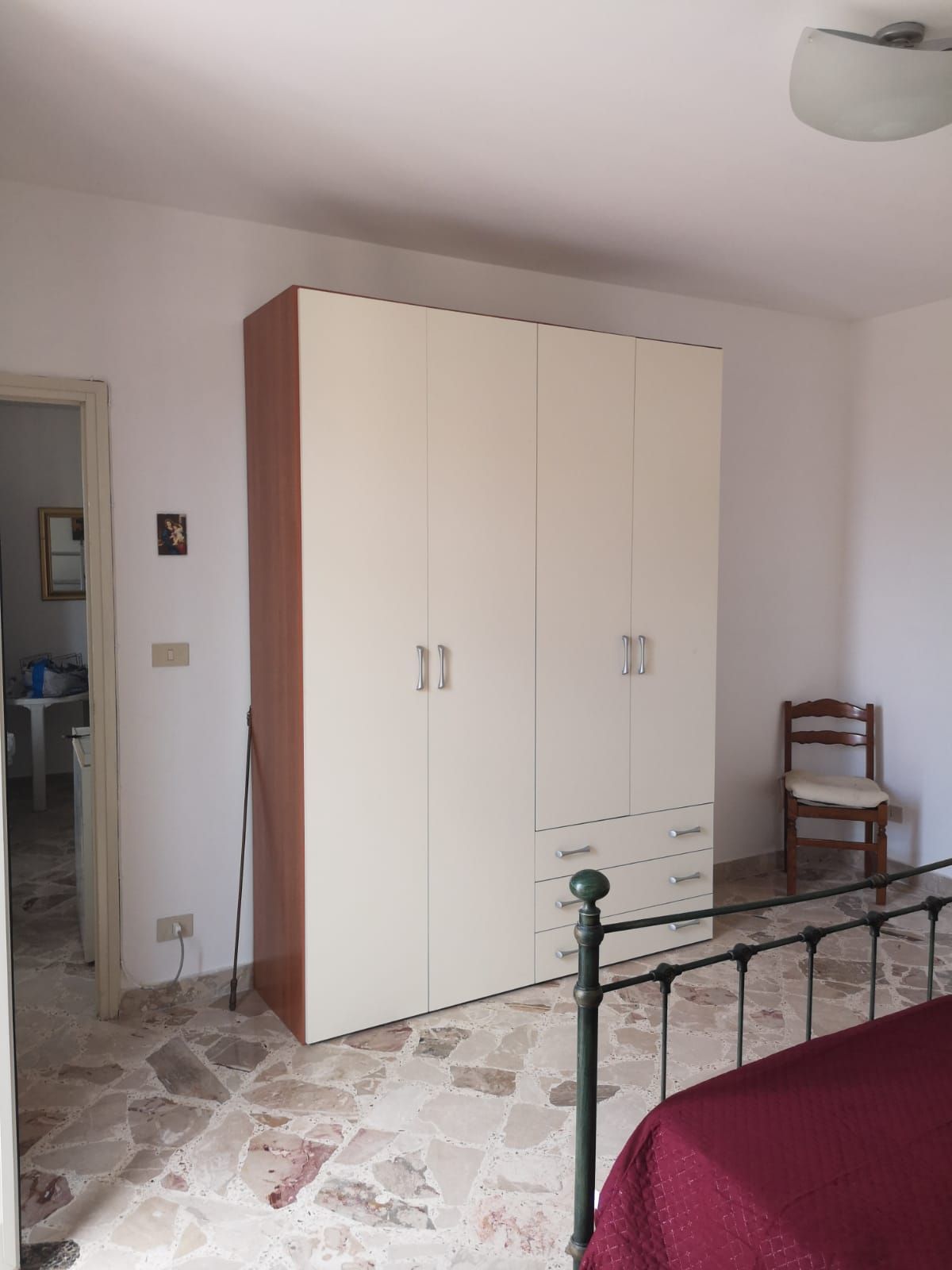 Una camera da letto con un armadio, una sedia e un letto.