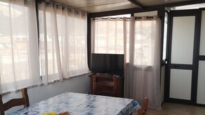 A dining area with a table covered in a blue patterned tablecloth, wooden chairs, and a bouquet of flowers. - 5 minutes from the square and the airport (Terrasini)