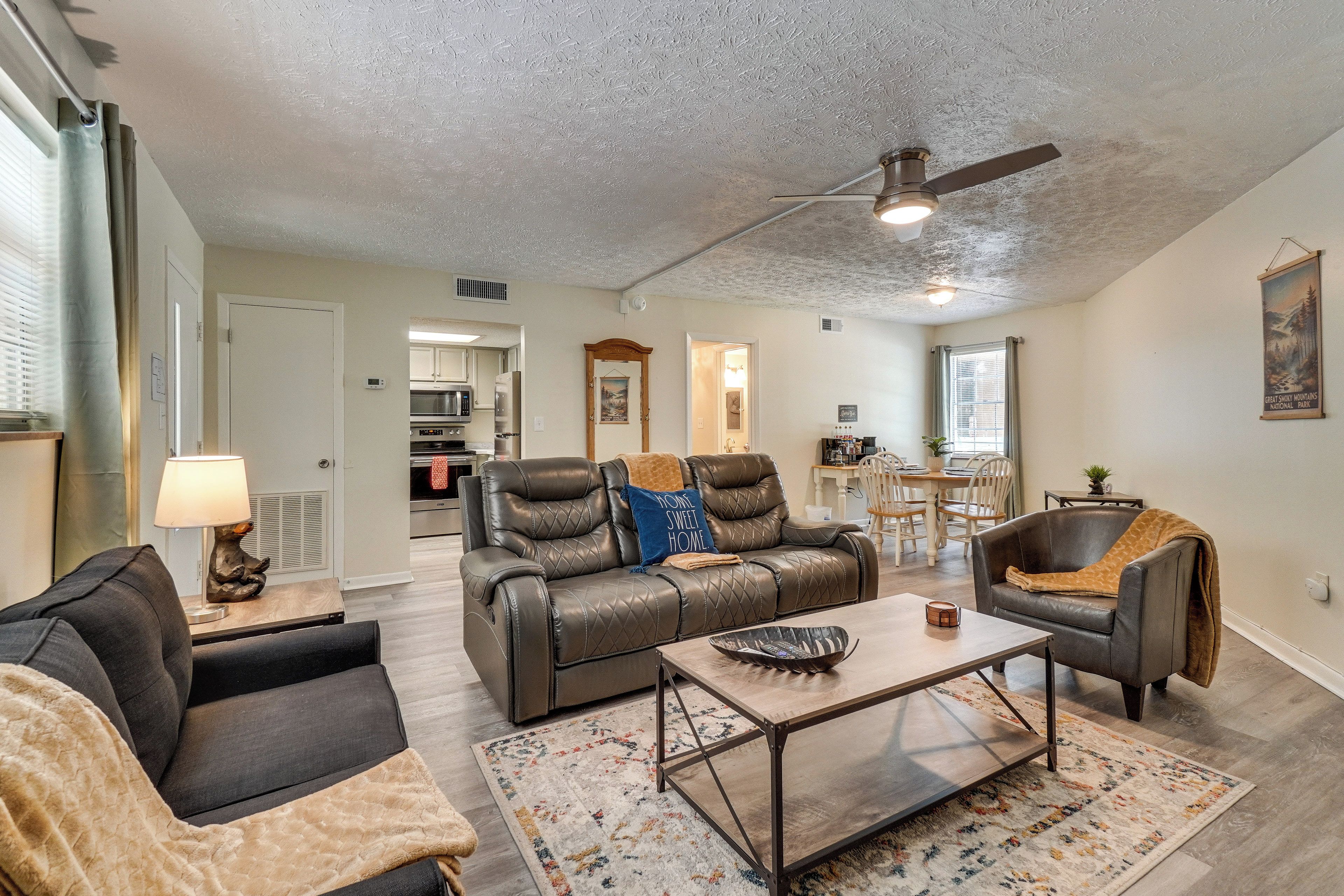 A spacious living room with a leather sofa, a coffee table, and a dining area with a table and chairs.