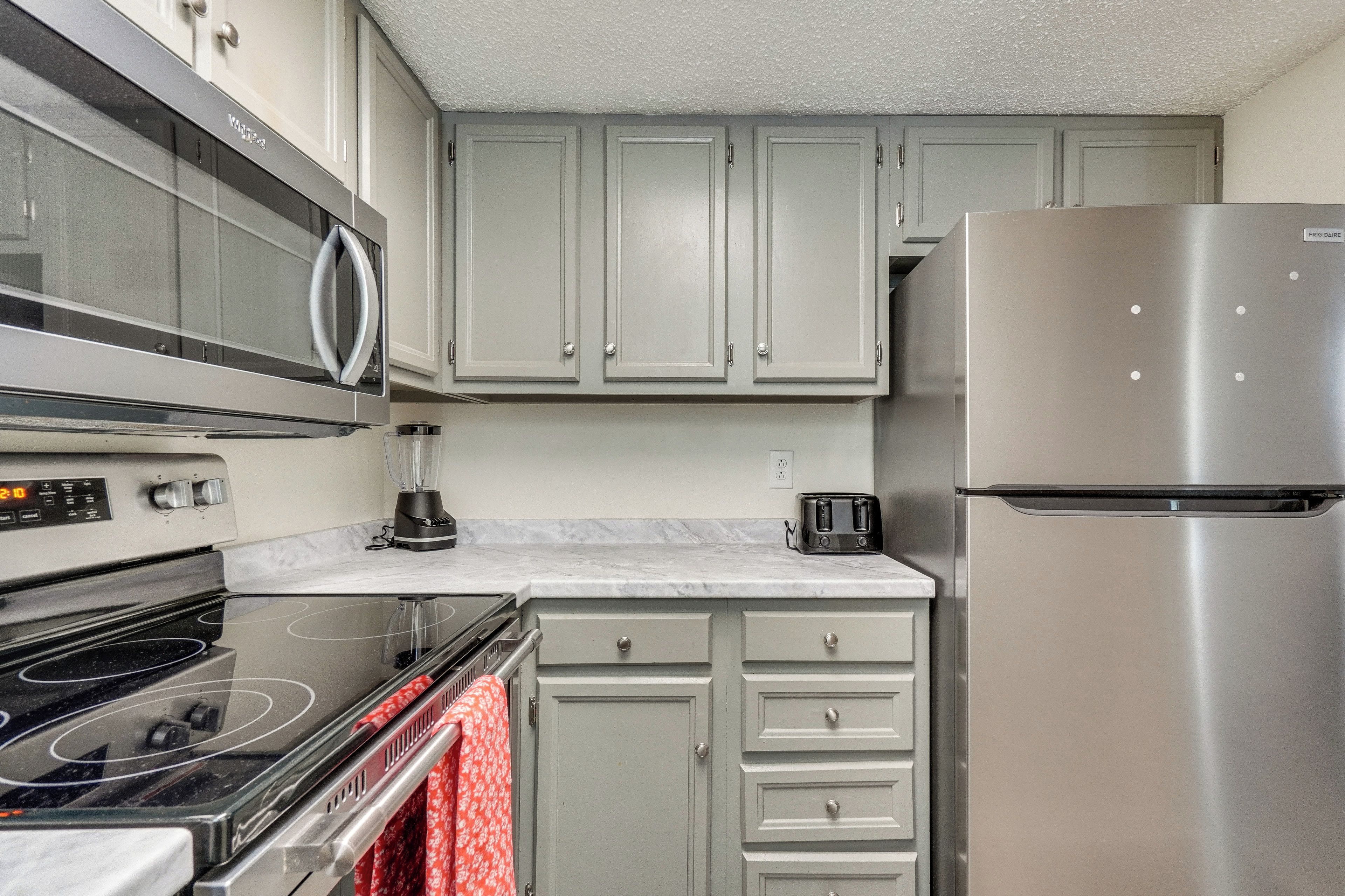 A kitchen with a stainless steel refrigerator, a microwave, an oven, and a toaster.