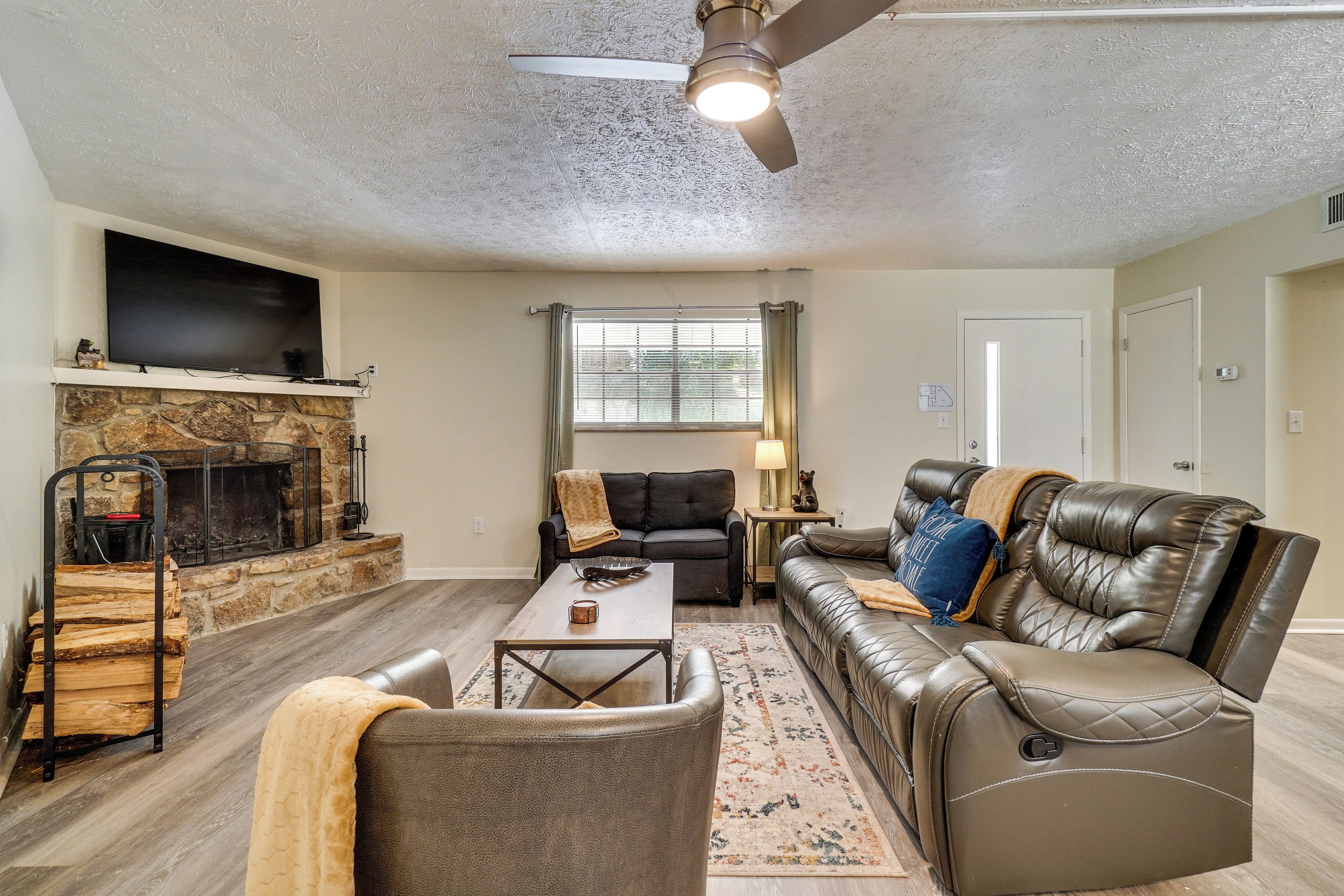 A living room with a fireplace, leather sofas, a coffee table, and a television.