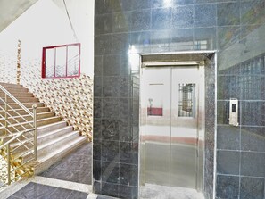 A staircase with a metal railing leading to a door with a glass panel. - Deluxe Room Saibala Lodge (Vellore)