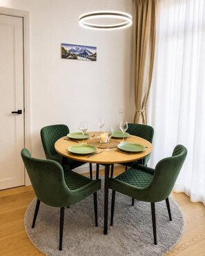 Uma área de refeições com uma mesa redonda, quatro cadeiras e um quadro na parede.