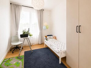 A child's bedroom with a bed, desk, chair, and a window with curtains.