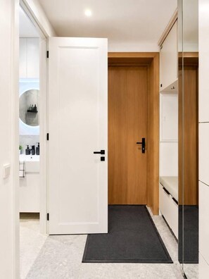 A hallway with a white door, a wooden door, and a black doormat. - Peaceful 2BR Mežaparks Stay with Free Parking (Rīga)