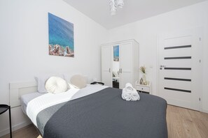 Un dormitorio con cama, almohadas, una mesita de noche con lámpara, un espejo y un armario.