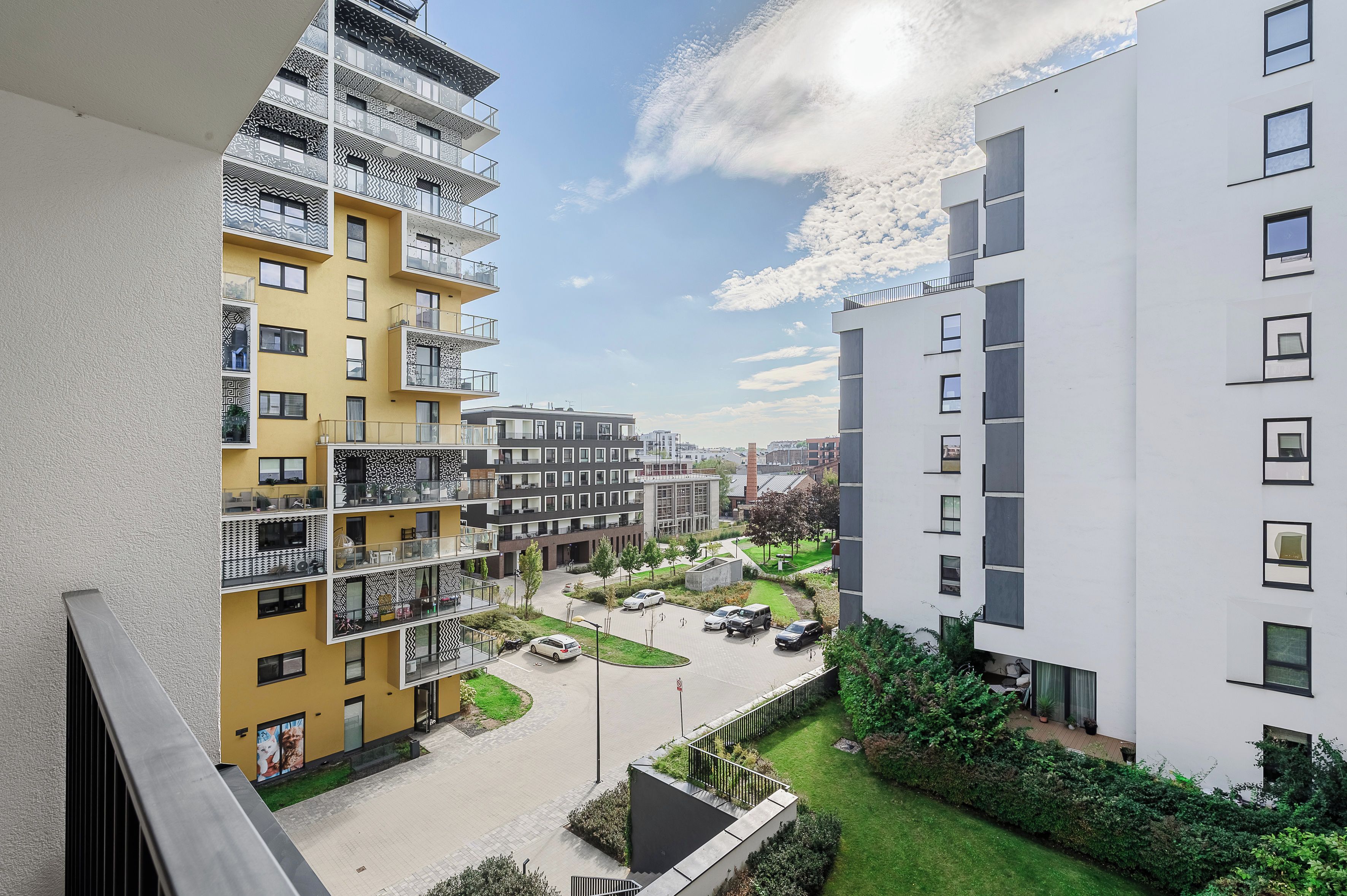 En flervåningsbyggnad med bostäder, balkonger, en parkeringsplats och en liten grön yta.