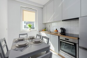 A modern kitchen with white cabinetry, a wooden countertop, and a built-in oven. - Lumina 2-room Apart near Skaryszewski (Warszawa)