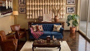 A living room with a blue sofa, leather armchairs, a wooden coffee table, and a chandelier. - Casona Tambo La Paz Hotel Boutique (La Paz)