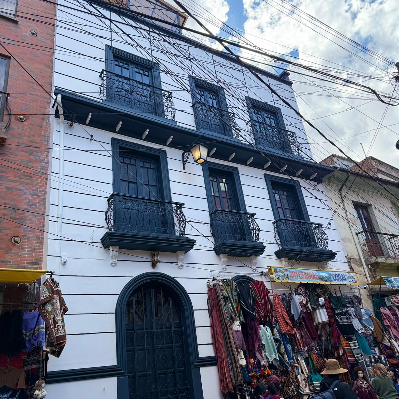 A building with multiple balconies and a ground-level shop with various items on display.