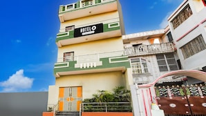 Un hotel de varios pisos con un llamativo letrero que dice 'HOTEL', una entrada con portones y una escalera que conduce a la entrada.