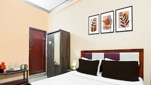 Habitación de hotel con cama, armario, espejo y tres cuadros en la pared.