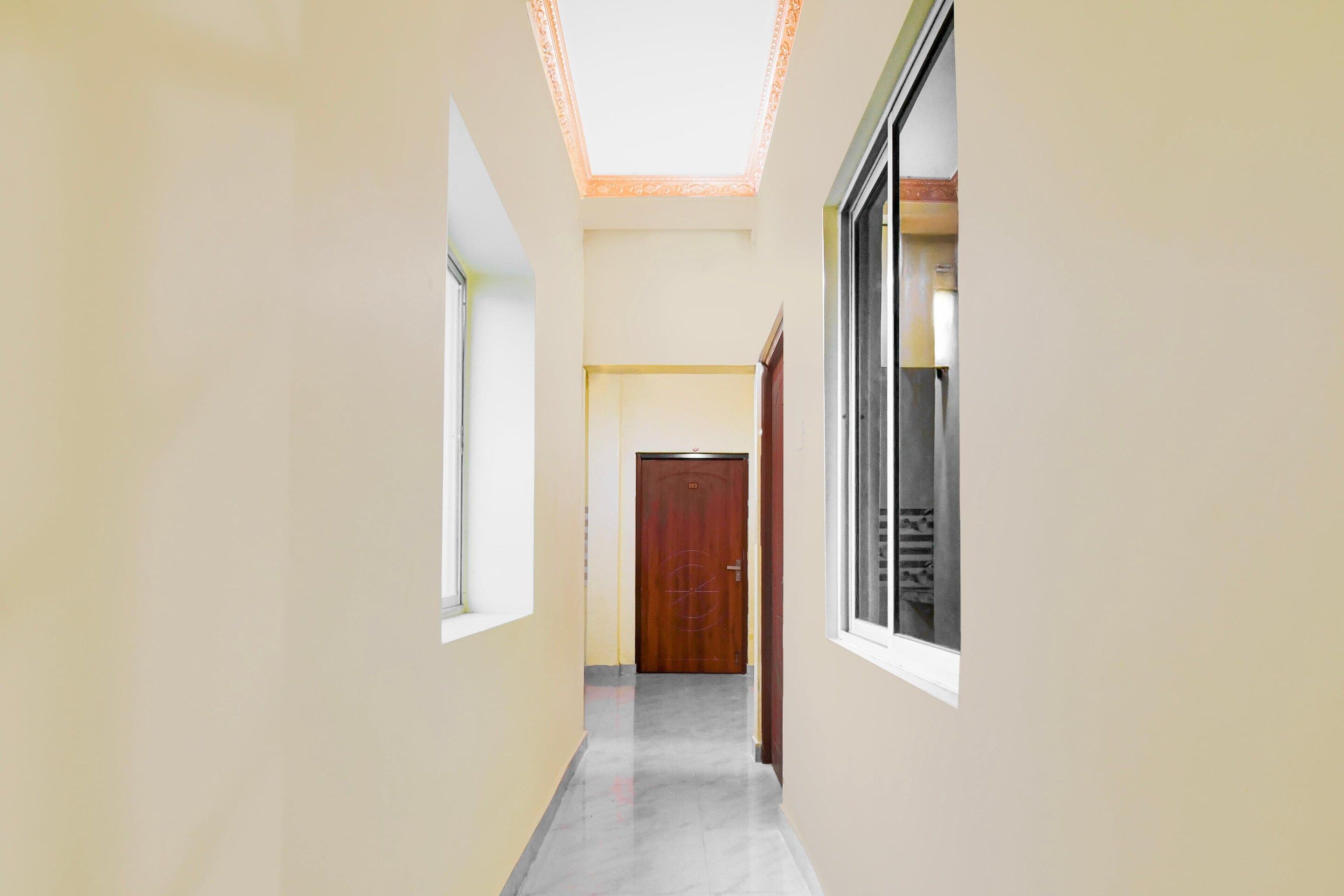 Un couloir avec une porte en bois, une fenêtre et une porte dotée d’un panneau de verre.