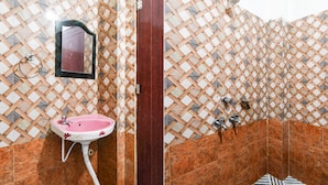 Un baño con un lavamanos rosa, un espejo y una zona de ducha.
