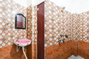 Une salle de bain avec un lavabo rose, un miroir et un espace douche.