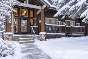 A snow-covered building with a stone staircase leading to a wooden door, a stone pillar, and a bench with snow on it. - TWO Queen Beds, No Stairs, Winter Hot Tub | Moose Mgmt 817 (Park City)