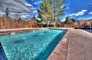 A rectangular swimming pool with clear blue water, surrounded by a wooden fence and trees. - TWO Queen Beds, No Stairs, Winter Hot Tub | Moose Mgmt 817 (Park City)