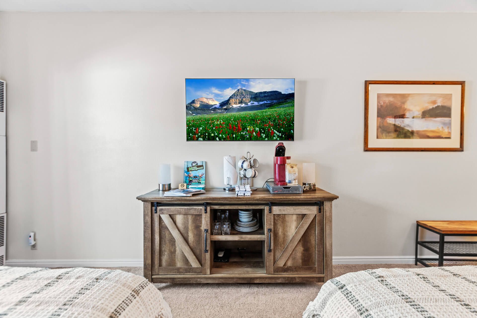 A bedroom with two beds, a wooden dresser with drawers, a framed picture on the wall, and a painting.