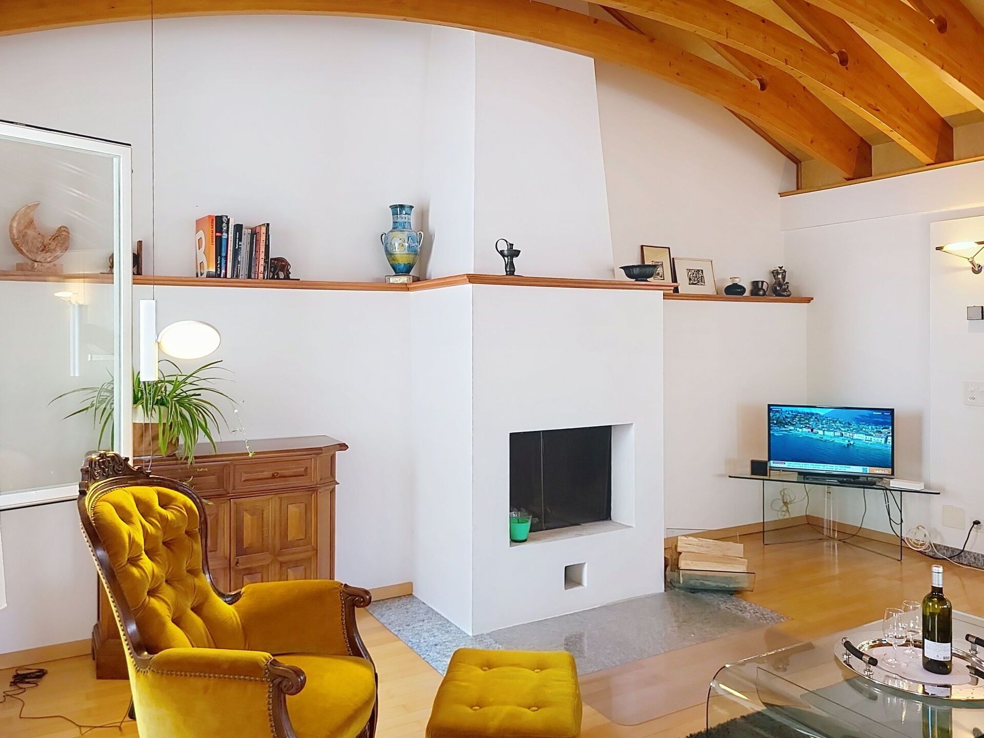 Un salon moderne avec une cheminée, un téléviseur et un fauteuil jaune.