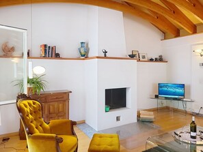Un salon moderne avec une cheminée, un téléviseur et un fauteuil jaune.
