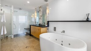Ein modernes Badezimmer mit Duschkabine aus Glas, einer freistehenden Badewanne und einem Waschtisch mit Marmor-Spritzschutz.