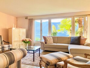 Ein Wohnzimmer mit einer Couch, Sesseln, einem Glastisch und einem Schrank.
