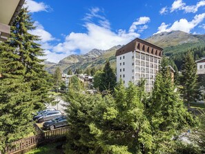 Ein Hotel mit Blick auf die Berge, umgeben von dichtem Grün und parkenden Autos.