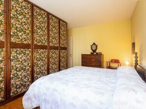 Ein Schlafzimmer mit einem großen Bett, einem Holzschrank mit floralem Wandpapier, einer Kommode und einem Stuhl.