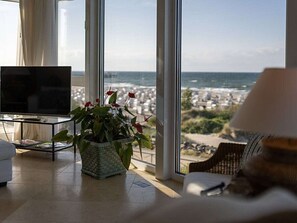 A living room with a television, a potted plant, and a view of the ocean. - 4 ,,ut de Franzosentid (Kuehlungsborn)