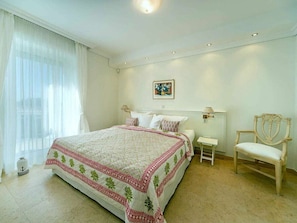 A bedroom with a large bed, a chair, a nightstand, and a painting on the wall. - 4 ,,ut de Franzosentid (Kuehlungsborn)