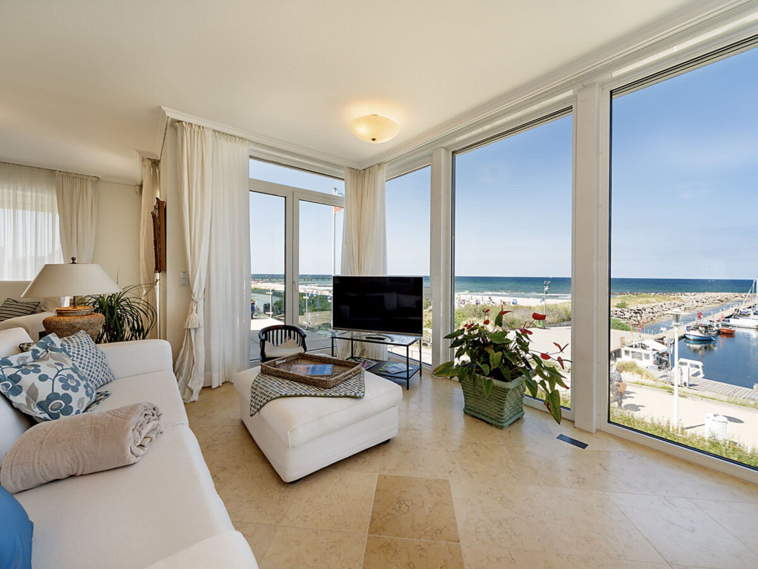 Un salón amplio con un televisor grande, asientos cómodos y vista al mar.