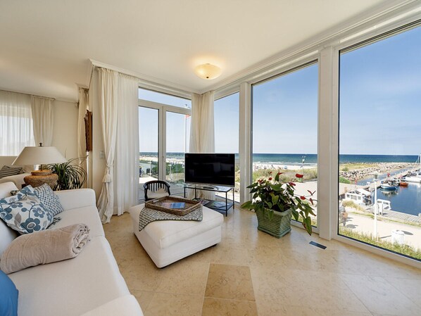 A spacious living room with a large TV, comfortable seating, and a view of the sea. - 4 ,,ut de Franzosentid (Kuehlungsborn)