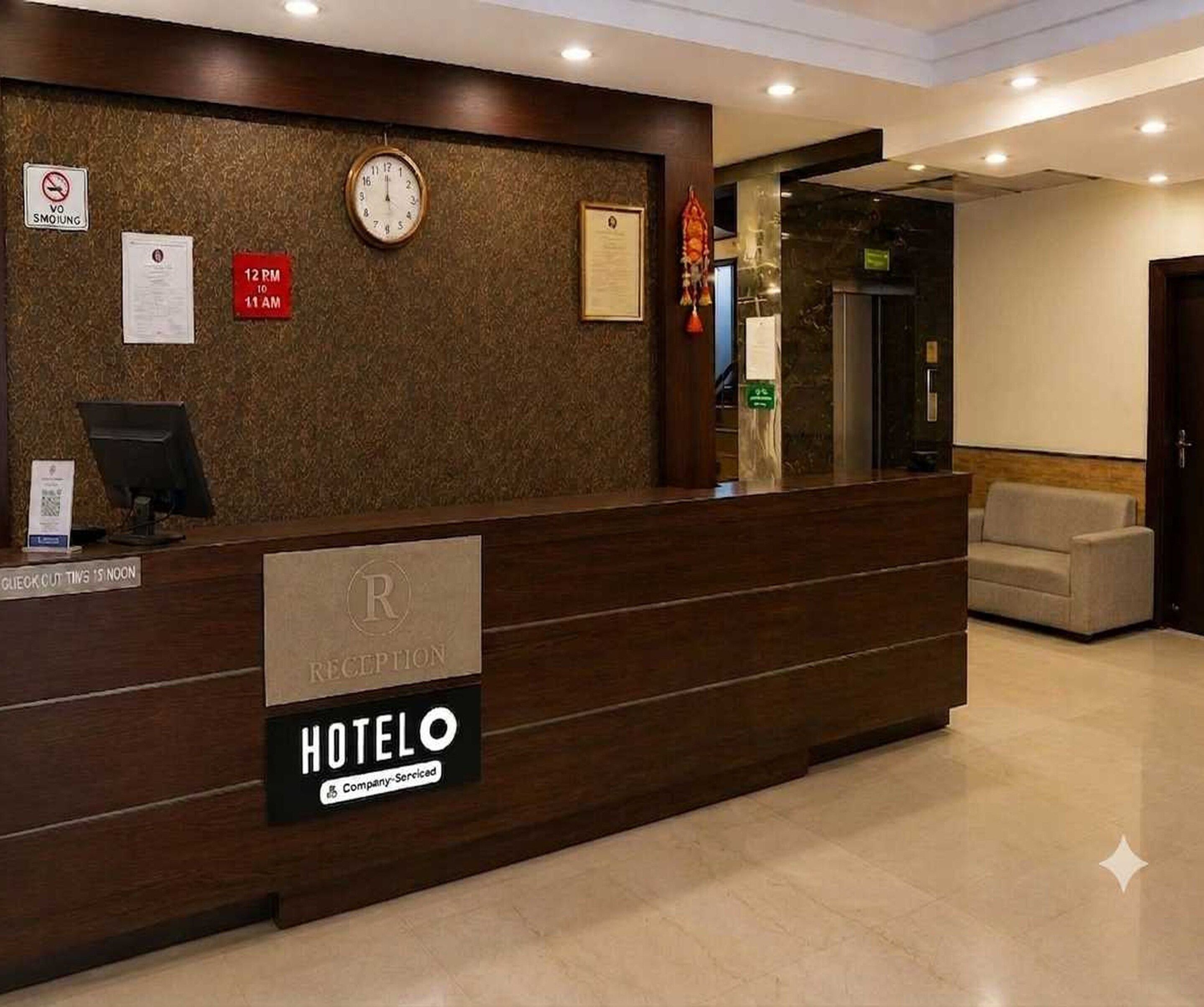 En hotellreception med en klocka, en skylt som visar att rökning inte är tillåtet och en skylt som anger utcheckningstiderna.