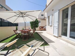 Eine Terrasse mit Tisch und Stühlen, einem großen Sonnenschirm und einer Hängematte.