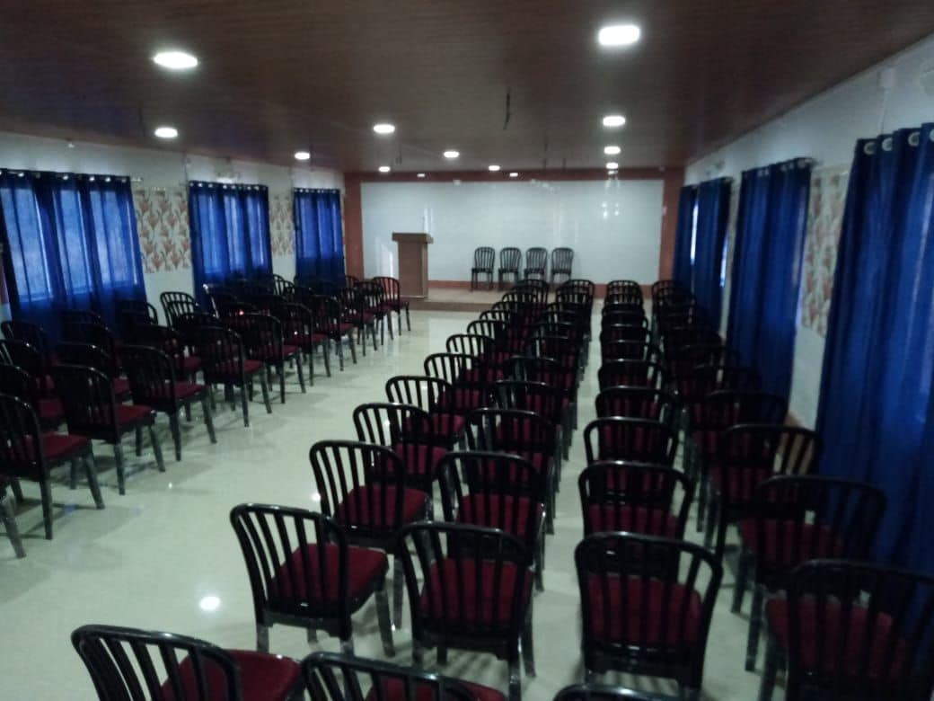 Uma sala de conferência com fileiras de cadeiras, um púlpito e um quadro branco.