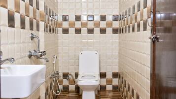 A bathroom with a toilet, sink, shower, and tiled walls.