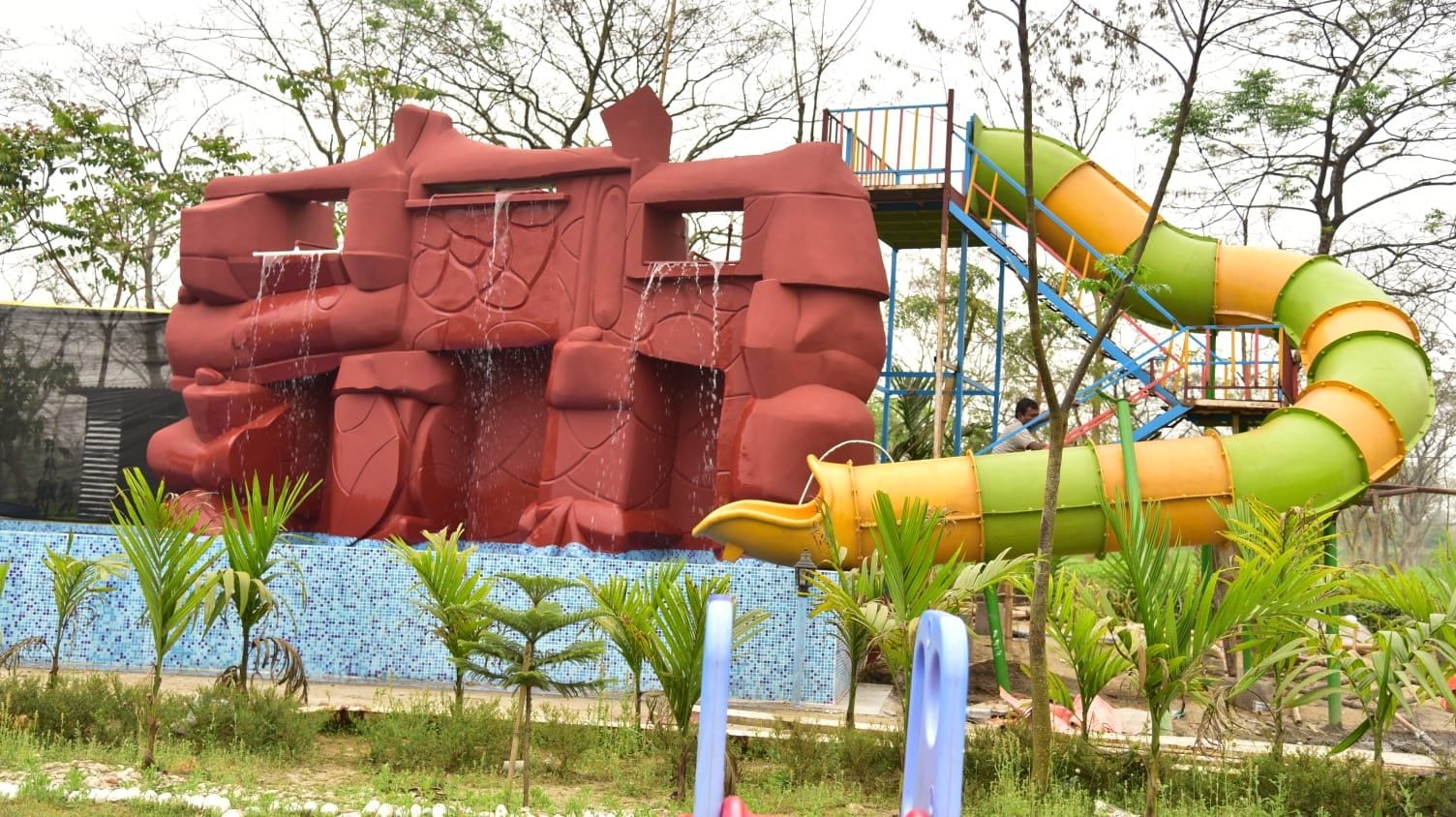 A water play area with a large red structure and a green slide.
