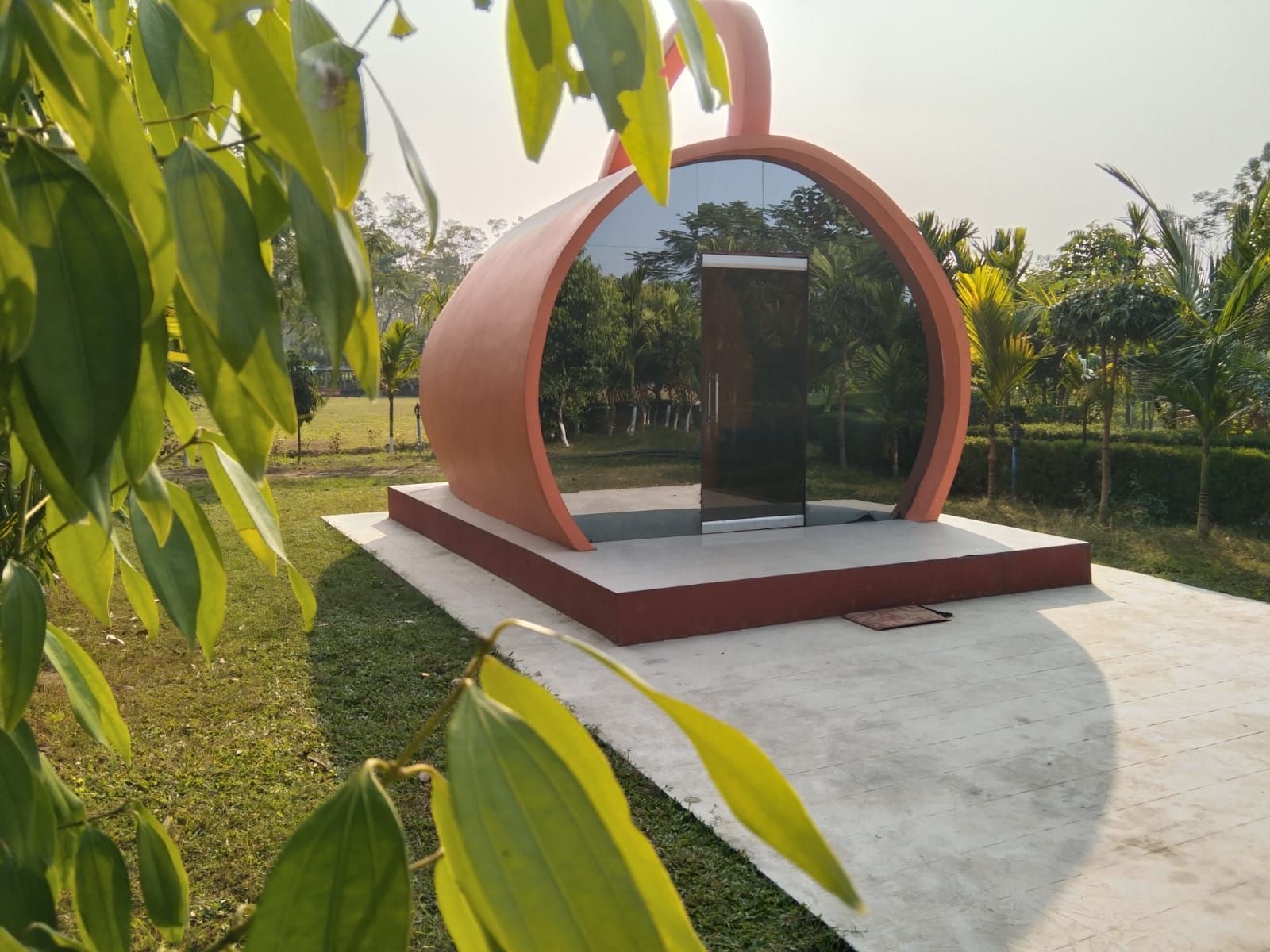 A modern outdoor structure with a circular design, a glass door, and a concrete base.