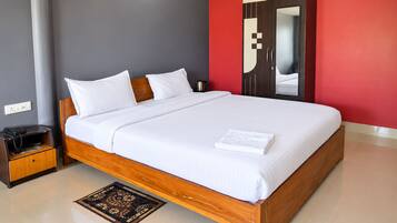 A neatly made bed with white linens, a wooden headboard, and a bedside table with a telephone and a magazine.
