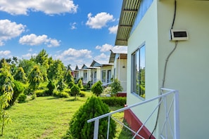 A row of single-story buildings with a grassy courtyard and a clear sky.