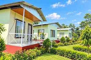 A two-story building with a balcony, surrounded by well-maintained gardens and trees.