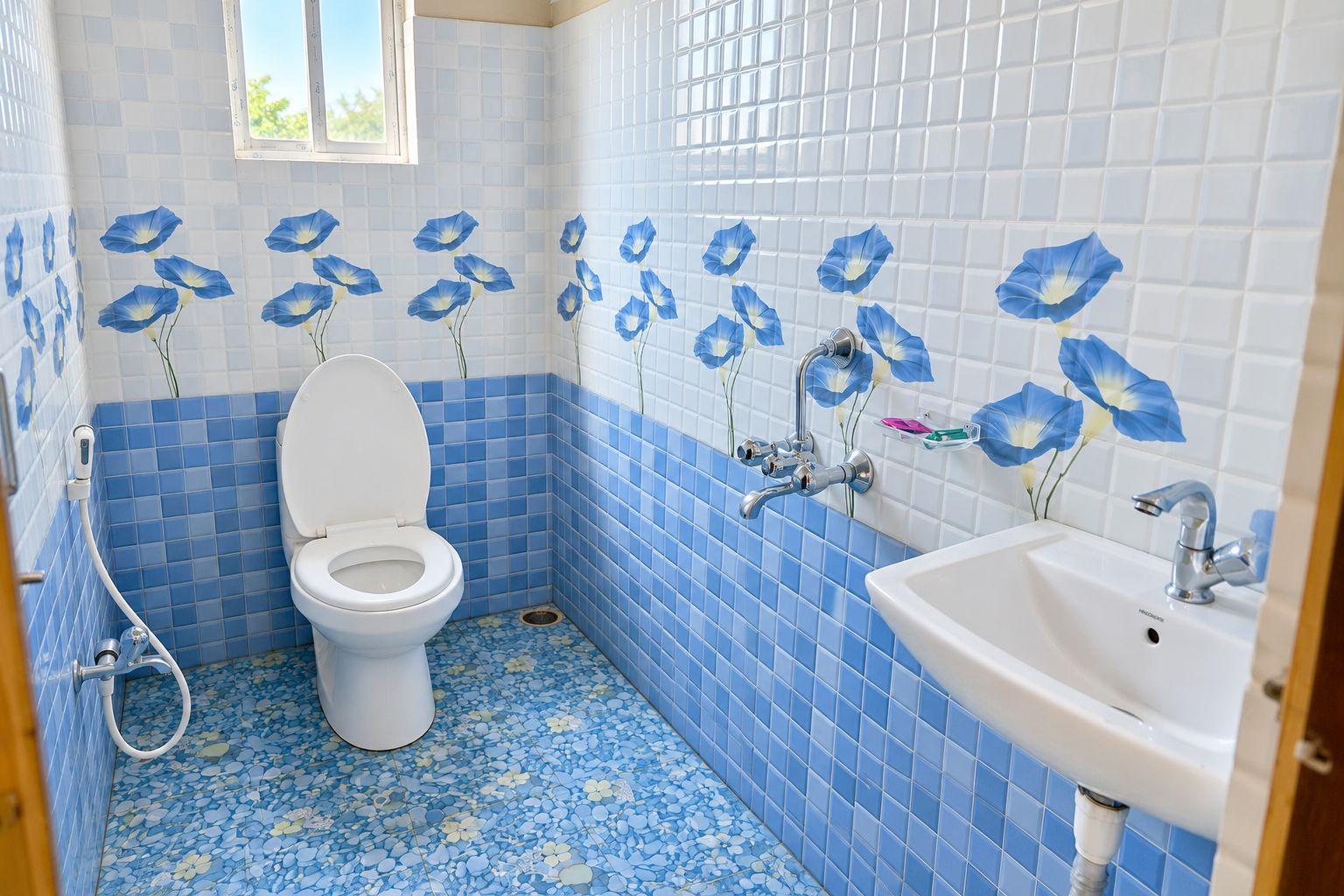 Een badkamer met toilet, wastafel en douche. De muren zijn betegeld met blauwe en witte patronen, en er is een raam boven het toilet.