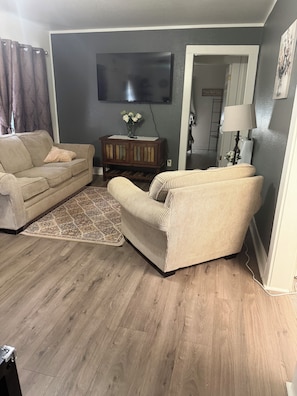 A living room with a sofa, armchair, and a small wooden side table with a vase of flowers. - Your Cozy Home away from Home (Panama)