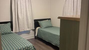 A room with two single beds, a ceiling fan, and a wooden floor.