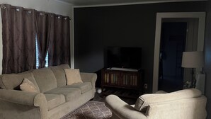Un salon avec un canapé, un fauteuil et un ventilateur de plafond.